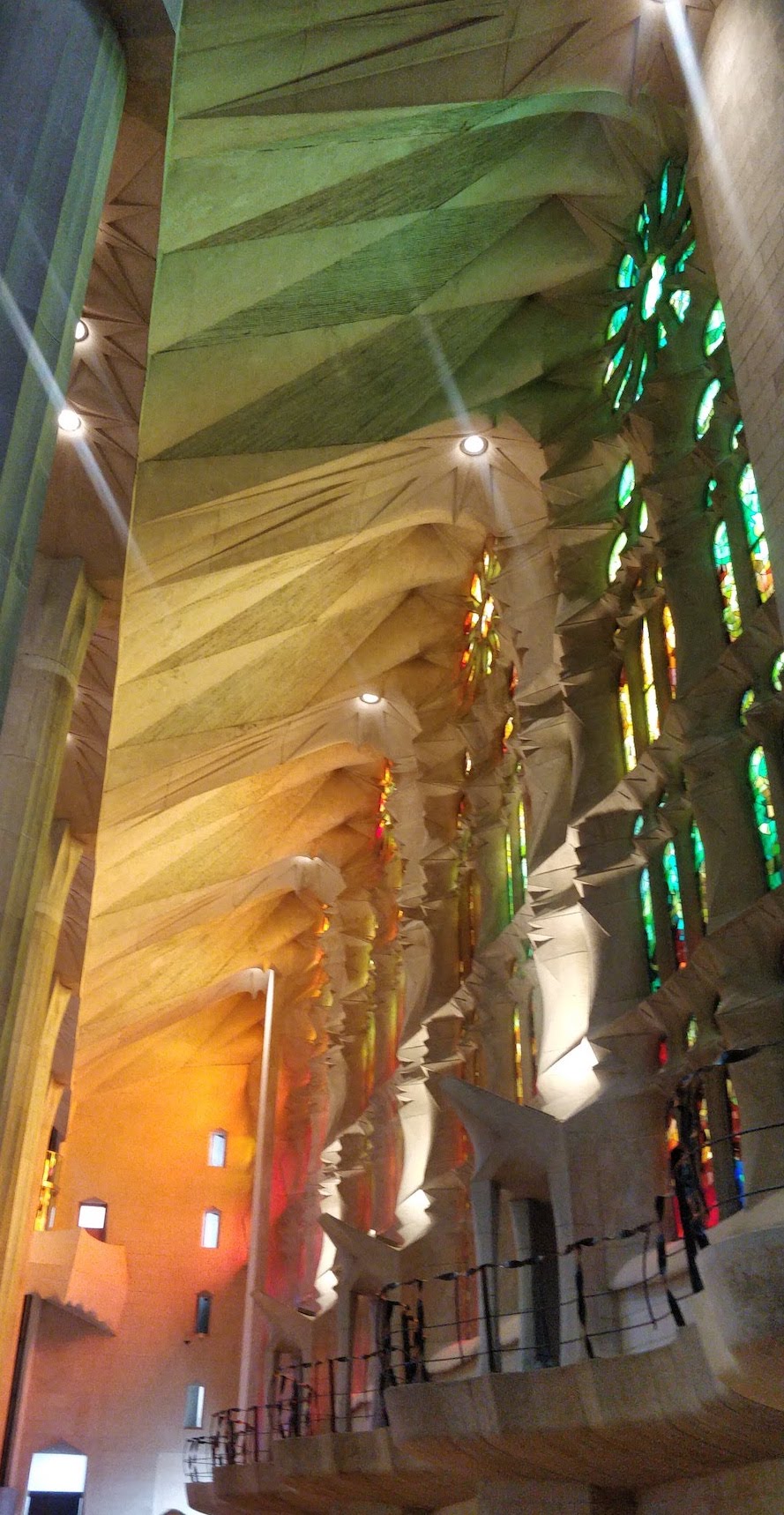 Picture of interior of La Sagrada Familia, with soaring ceilings and light streaming in through colored stained glass windows.